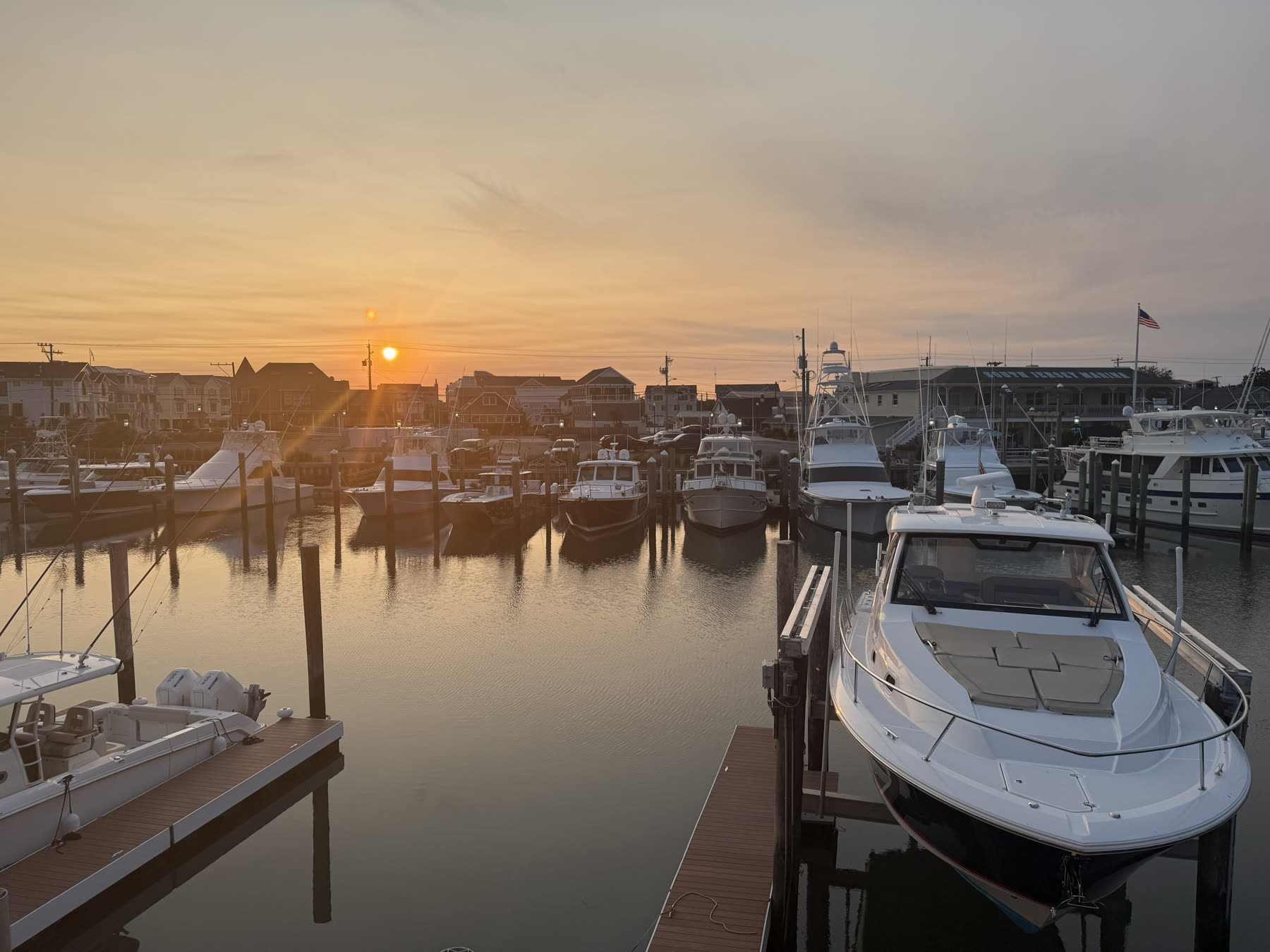 Golden morning light over the Cape May yacht marina with boats and an American flag