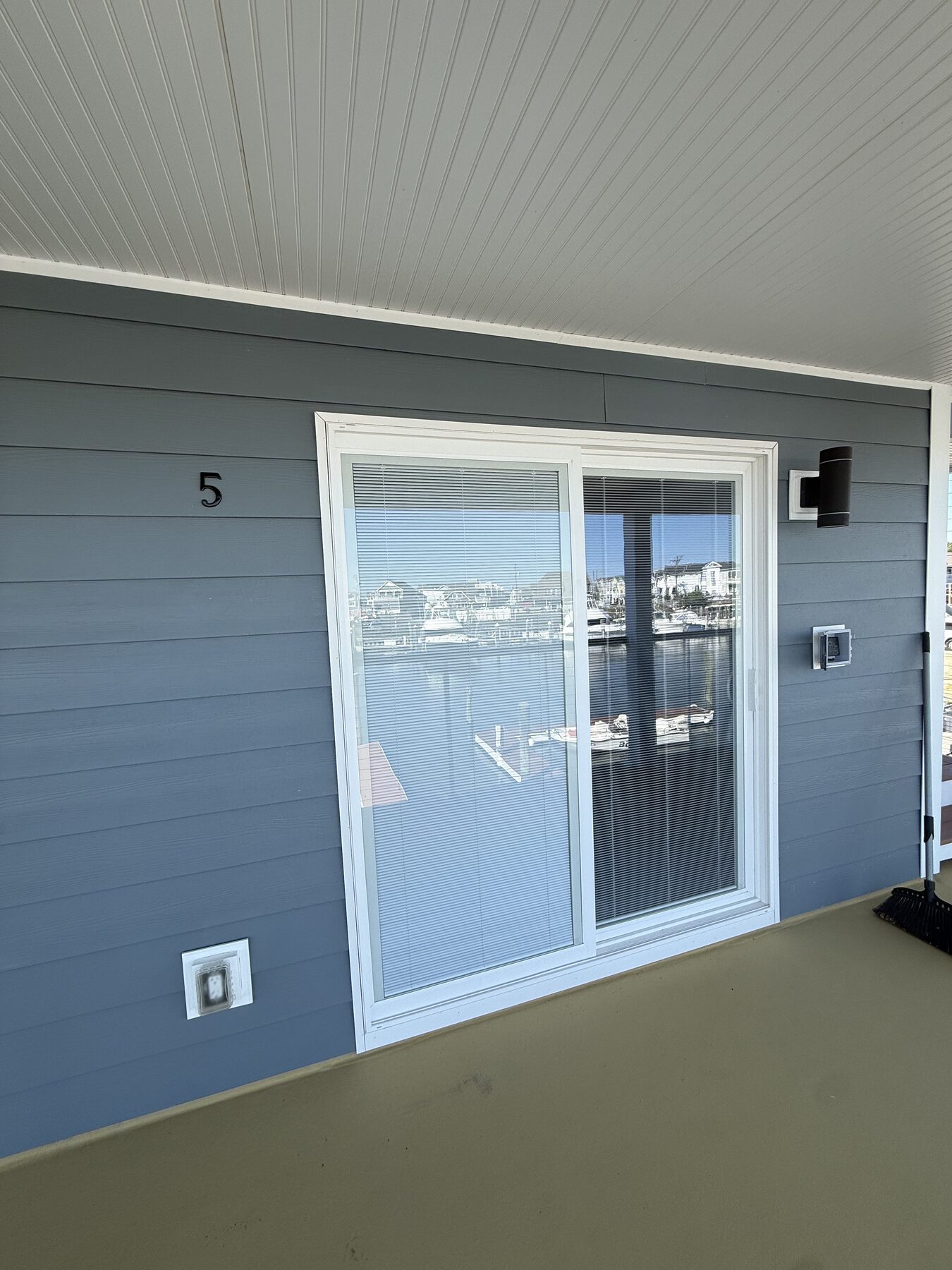 Sliding glass entry door for Unit 5 at Yacht Avenue Condos, with the Cape May yacht marina reflected in the glass