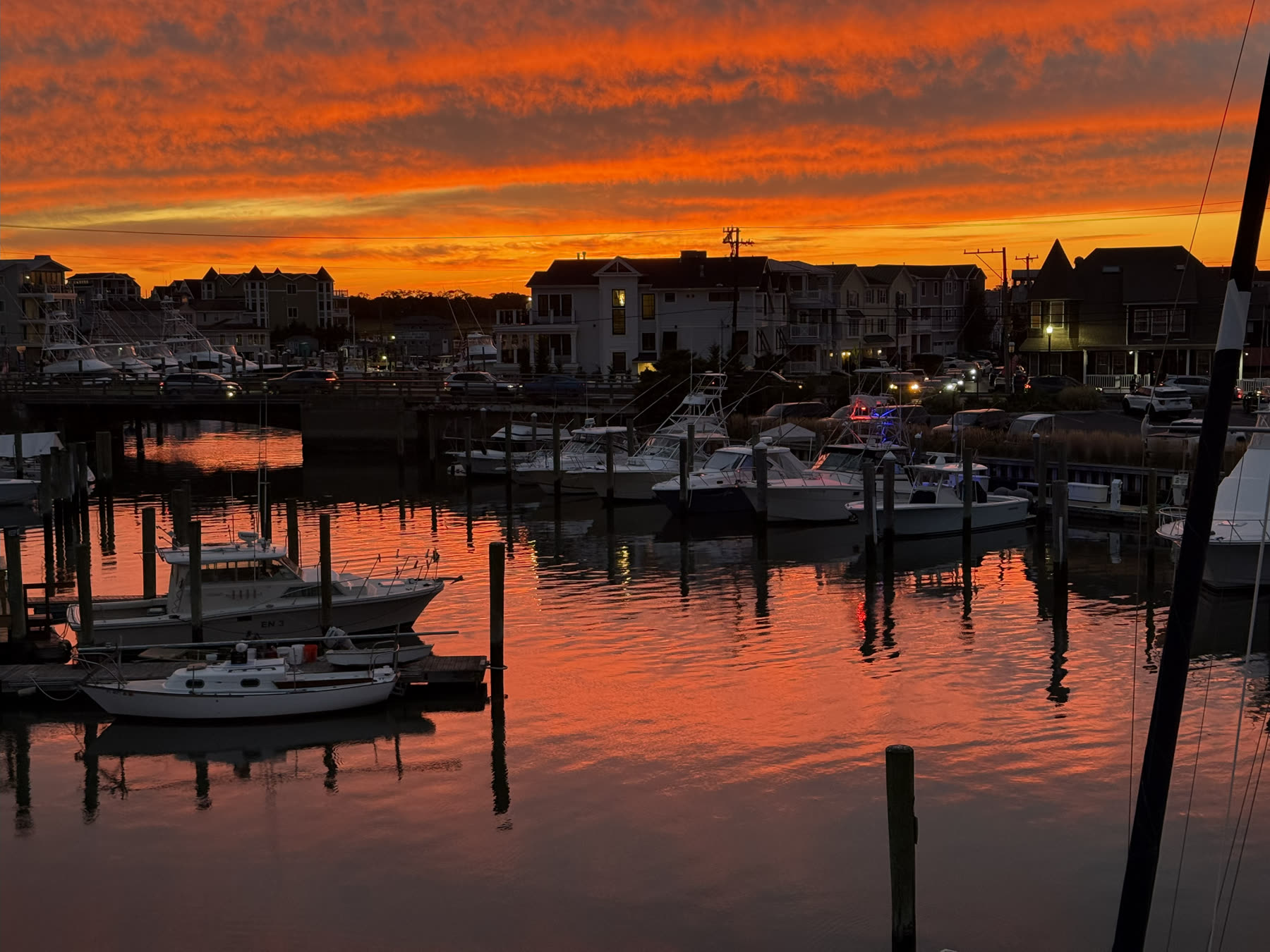 Fiery orange sunset over the Cape May yacht marina with docked boats reflecting in the water