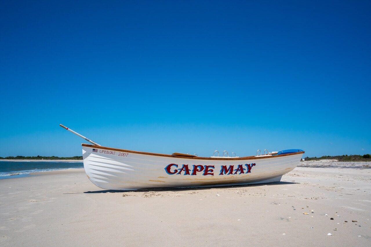 Classic Cape May lifeboat on the beach under a clear blue sky